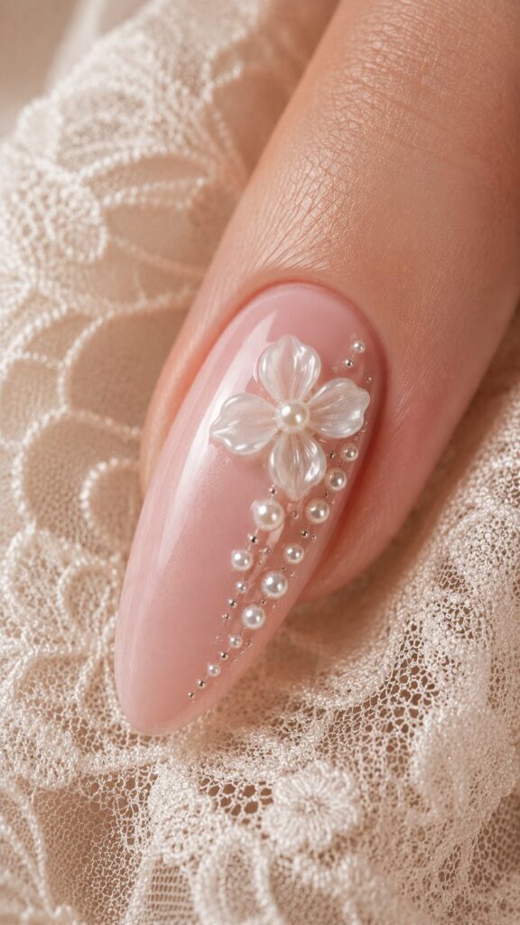 Uña con flor 3D nacarada con cascada de perlas en degradé sobre rosa suave para novia elegante en tendencia